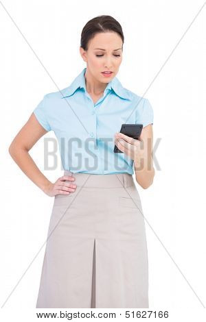 Worried classy businesswoman on white background looking at her calculator