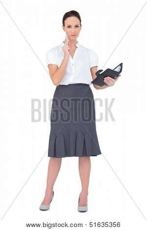 Thoughtful businesswoman holding her datebook on white background