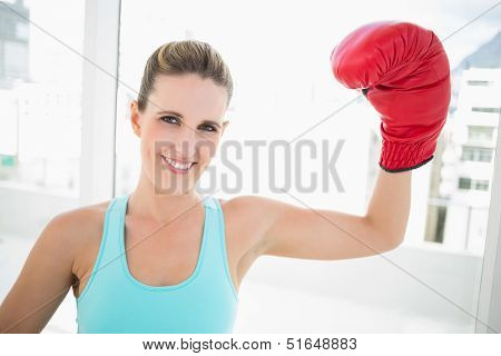 Woman rising her boxing glove up smiling at camera