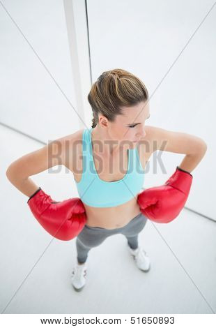 Fit woman with boxing gloves posing looking away