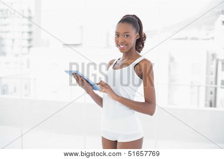 Fit pretty woman holding digital tablet in bright fitness studio