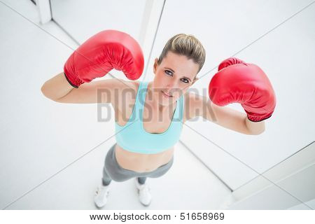 Fit woman with boxing gloves posing looking at camera