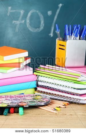 Office supplies on table on school board background 