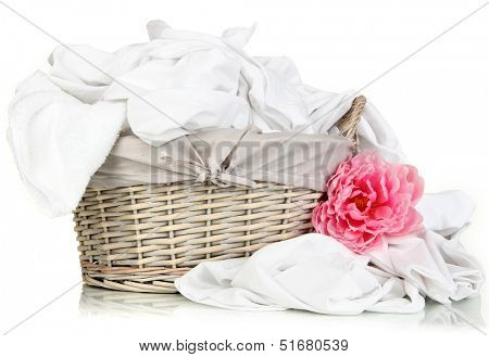 Rumpled bedding sheets in wicker basket isolated on white