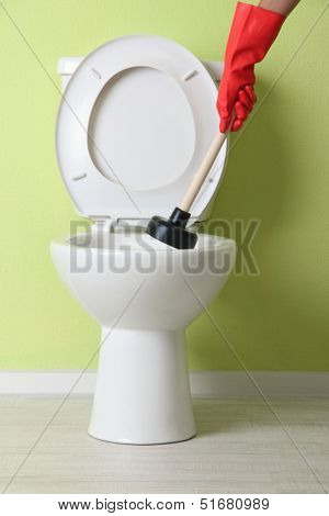Woman uses a plunger to unclog a toilet bowl in a bathroom