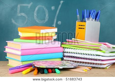Office supplies on table on school board background 