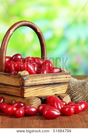 Fresh cornel berries in basket on wooden table
