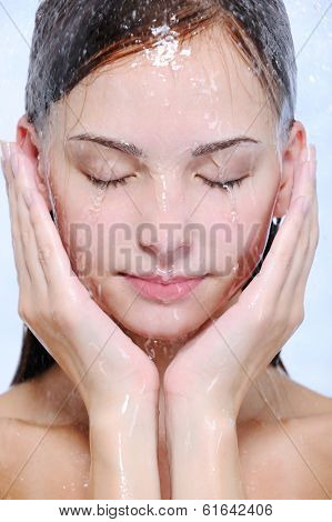 Streams of water on the young beautiful female face - close-up