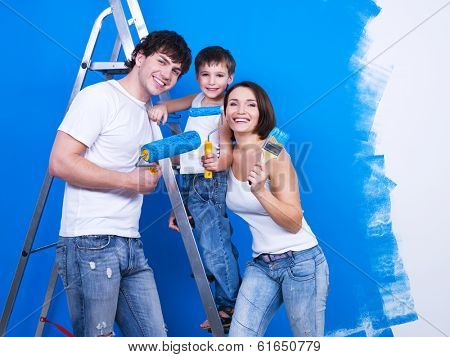 Friendly smiling family with young son painting the wall
