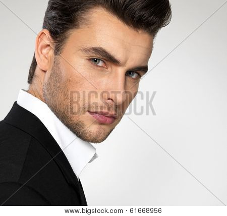 Fashion young businessman black suit casual  poses at studio