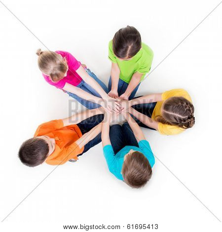 Group of smiling children sitting on the floor in a circle holding hands - isolated on white.