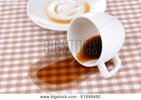 Overturned cup of coffee on table close-up