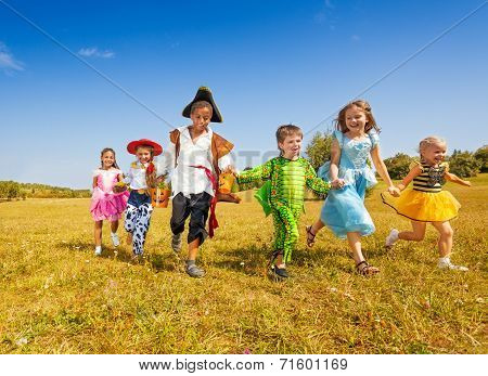 Large group of kids in Halloween costumes run