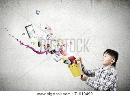 Young boy splashing colorful paint from bucket