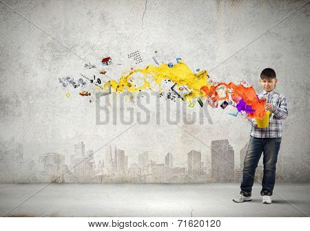 Young boy splashing colorful paint from bucket