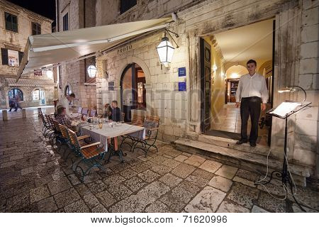 DUBROVNIK, CROATIA - MAY 27, 2014: Waiter standing at the entrance of Proto restaurant. Dubrovnik has many restaurants which offer traditional Dalmatian cuisine and some great wine lists.