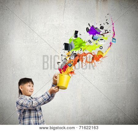 Young boy splashing colorful paint from bucket