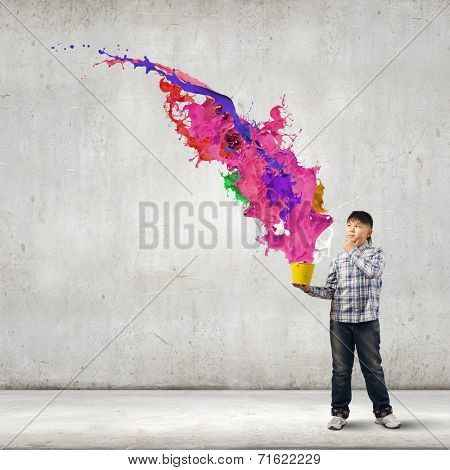Young boy splashing colorful paint from bucket