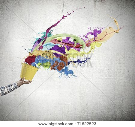 Close up of hand splashing colorful paint from bucket
