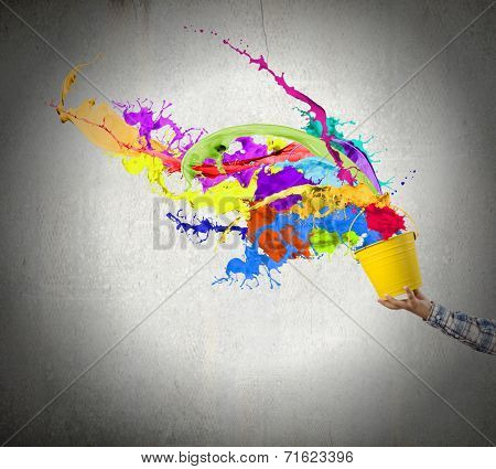 Close up of hand splashing colorful paint from bucket