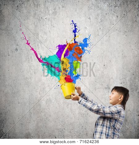 Young boy splashing colorful paint from bucket