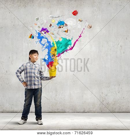 Young boy splashing colorful paint from bucket