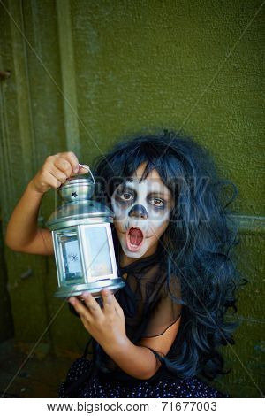 Weird Halloween girl with lantern looking at camera