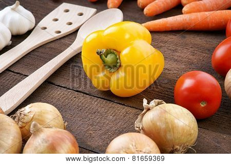 Yellow pepper with vegetables and cooking spoons