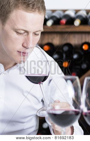 Male Winemaker Smelling A Red Wineglass.