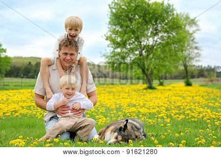 Father, Children, And Dog Relaxing In Flower Meadow