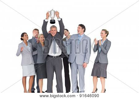 Excited business team cheering at camera with trophy on white background