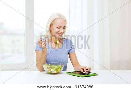 healthy eating, dieting and people concept - smiling young woman with tablet pc computer eating vegetable salad at home