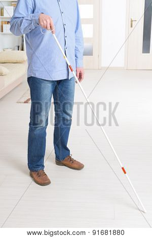 Blind man with white stick and dark glasses at home