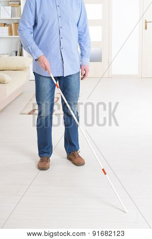 Blind man with white stick and dark glasses at home