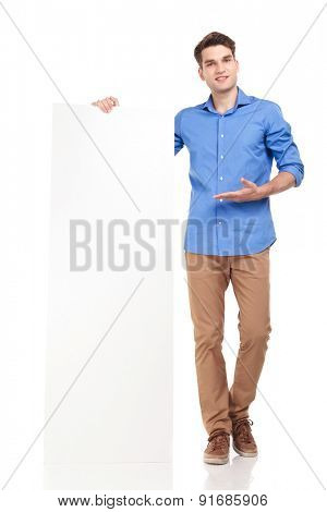 Attractive young fashion man presenting a white board, while smling.