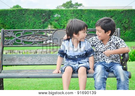 Little happy sibling boy sitting together in the gardent