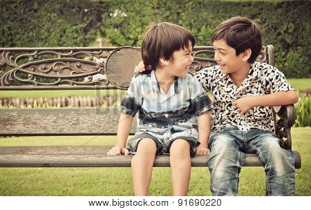 Little happy sibling boy sitting together in the gardent
