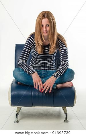 Beautiful stylish young woman sitting cross-legged on a couch