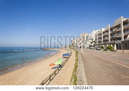 Beach ocean tidal pool swimmers with holiday apartments coastline landscape.