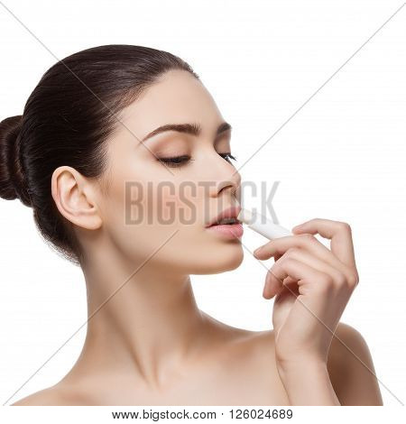 Beautiful young woman applying chapstick to lips. Isolated over white background. Copy space. Square composition.