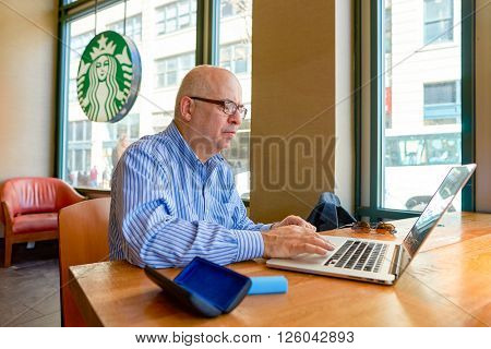 NEW YORK - CIRCA MARCH 2016: man in Starbucks Cafe. Starbucks Corporation is an American global coffee company and coffeehouse chain based in Seattle, Washington