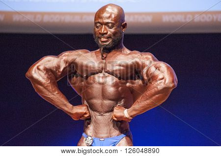 MAASTRICHT THE NETHERLANDS - OCTOBER 25 2015: Male bodybuilder Elias Bogane flexes his muscles and shows his best physique in a front lats spread pose on stage at the World Grandprix Bodybuilding and Fitness of the WBBF-WFF