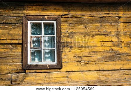 Yellow timbered wooden loghouse wall with window