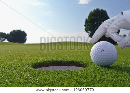 a man push a ball in a golf hole