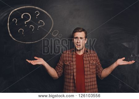 Handsome Young Freelancer At A Loss On The Background Of Chalkboard