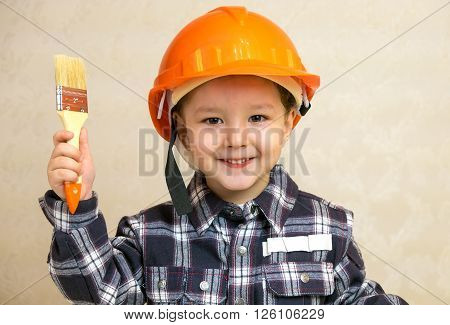 Little boy in the construction helmet with a brush.