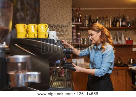 equipment, coffee shop, people and technology concept - barista woman making coffee by machine at cafe bar or restaurant kitchen