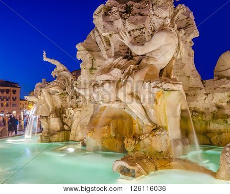 Illuminated at night the fontana del Moro (the Moor Fountain) on Piazza Navona on the Sant'Agnese in Agone church background, Rome, Italy