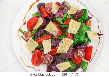 Fresh Mediterranean salad with prosciutto, parmesan cheese and vegetables.