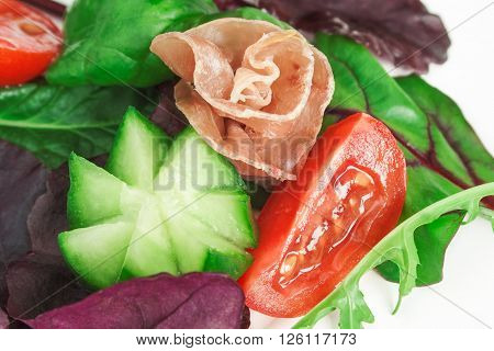 Close up image of fresh Mediterranean salad with prosciutto, and vegetables.